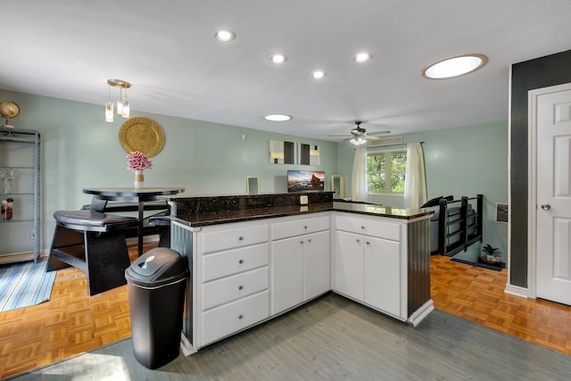 kitchen featuring pendant lighting, kitchen peninsula, parquet floors, ceiling fan, and white cabinetry