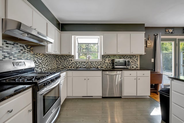 kitchen featuring white cabinetry, hardwood / wood-style floors, stainless steel appliances, and decorative backsplash