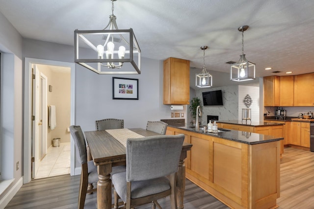 dining room featuring light wood-type flooring, baseboards, a textured ceiling, and a chandelier