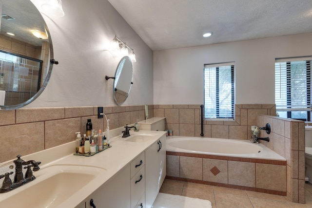 bathroom with a bath, tile patterned flooring, a textured ceiling, and a sink