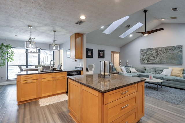 kitchen featuring wood finished floors, visible vents, a kitchen island, a sink, and a textured ceiling