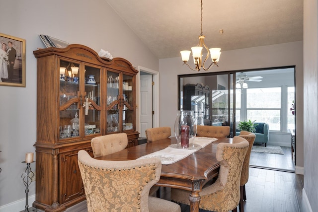 dining area featuring ceiling fan with notable chandelier, lofted ceiling, wood finished floors, and baseboards