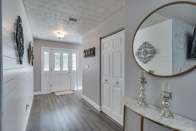 entryway featuring dark wood finished floors, baseboards, visible vents, and a textured ceiling