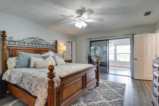 bedroom with visible vents, a textured ceiling, wood finished floors, and access to outside