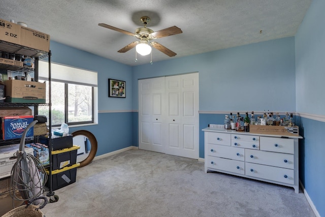 interior space with ceiling fan, carpet, baseboards, and a textured ceiling