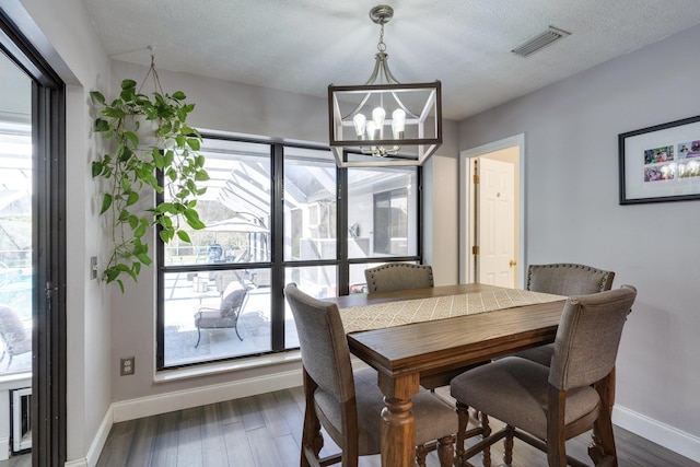 dining room with a chandelier, visible vents, baseboards, and wood finished floors