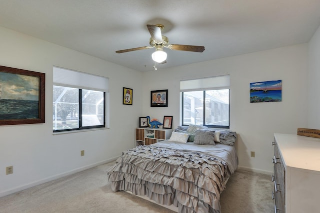 bedroom with multiple windows, light carpet, and baseboards