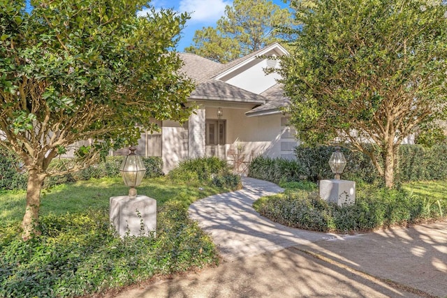 view of front of property with a shingled roof and stucco siding