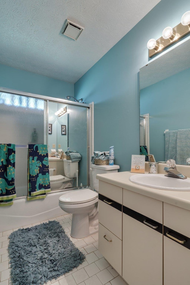 bathroom with toilet, a textured ceiling, tile patterned flooring, enclosed tub / shower combo, and vanity