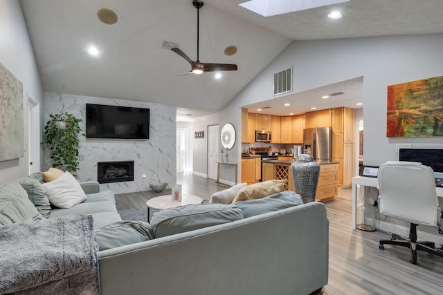 living area with light wood-style floors, a fireplace, visible vents, and ceiling fan