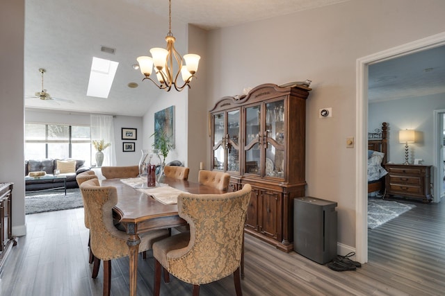 dining room featuring visible vents, wood finished floors, vaulted ceiling with skylight, baseboards, and ceiling fan