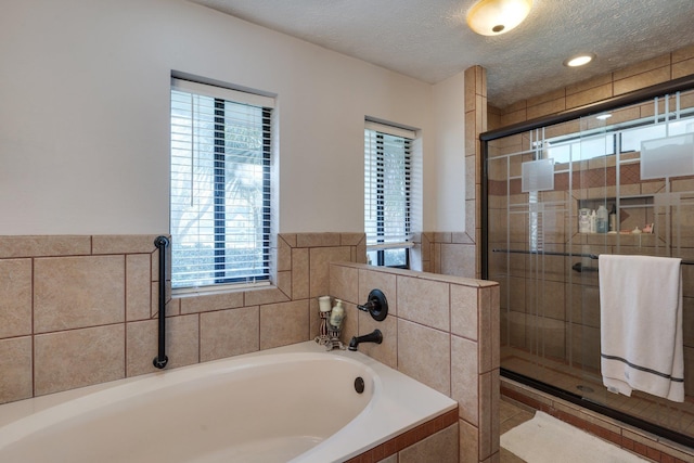 bathroom featuring a shower stall, a textured ceiling, and a garden tub