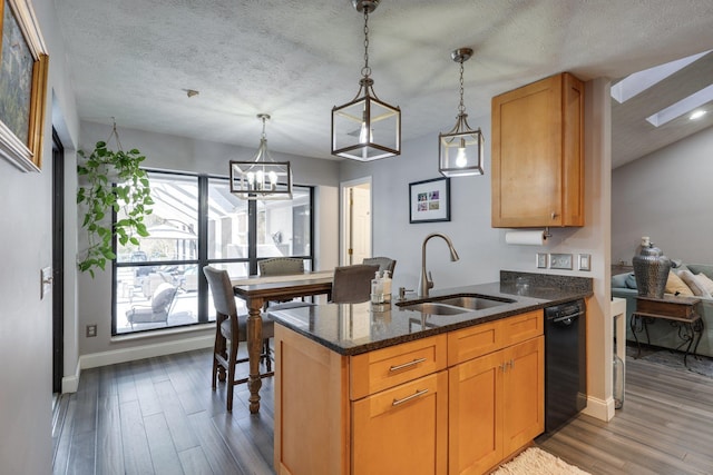 kitchen with dark stone countertops, wood finished floors, a peninsula, a sink, and dishwasher