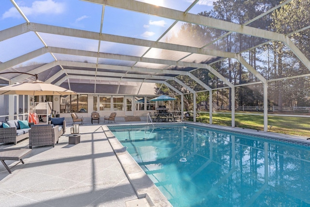 outdoor pool with glass enclosure, a patio, and an outdoor hangout area