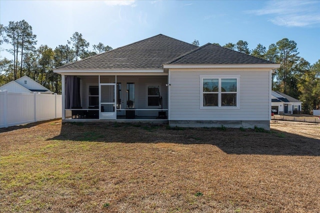 rear view of house with a sunroom and a yard