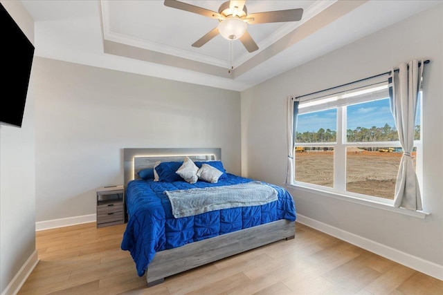 bedroom with a raised ceiling, ornamental molding, ceiling fan, and light wood-type flooring