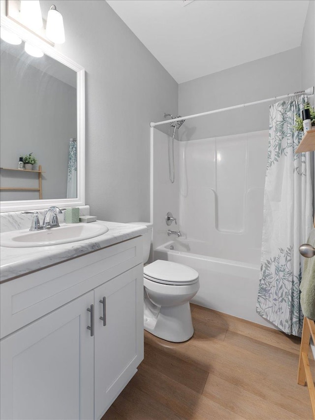 full bathroom with hardwood / wood-style flooring, vanity, shower / bathtub combination with curtain, and toilet