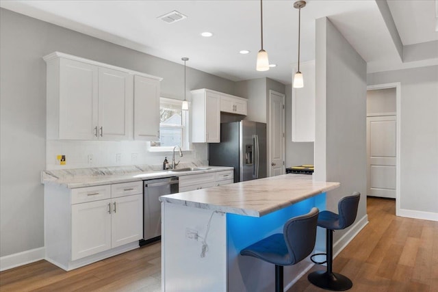 kitchen featuring a breakfast bar, tasteful backsplash, appliances with stainless steel finishes, pendant lighting, and white cabinets