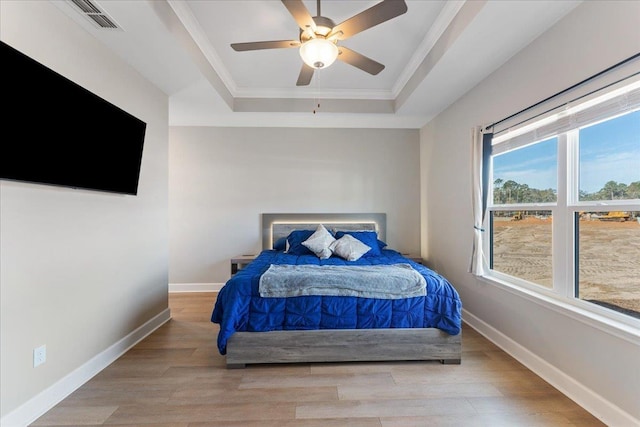 bedroom featuring crown molding, ceiling fan, a tray ceiling, and light hardwood / wood-style floors