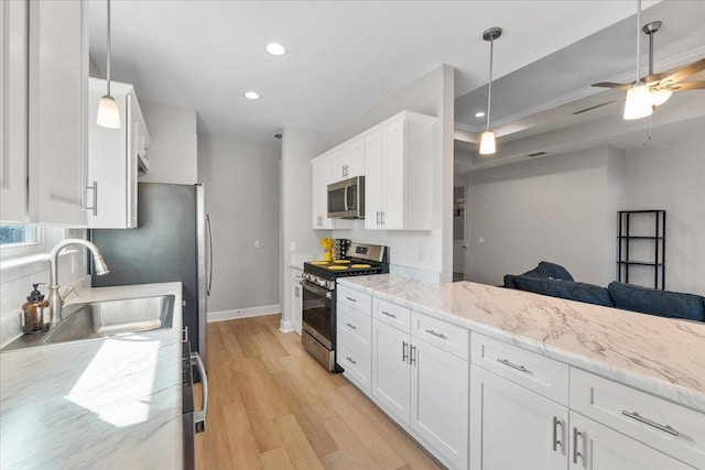 kitchen with sink, hanging light fixtures, light wood-type flooring, stainless steel appliances, and white cabinets