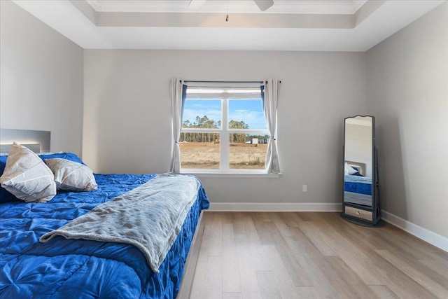 bedroom featuring hardwood / wood-style floors, ornamental molding, a raised ceiling, and ceiling fan