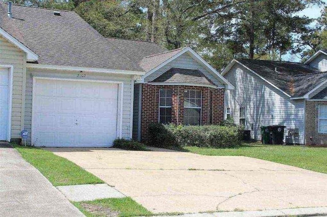 view of front facade featuring an attached garage, a shingled roof, concrete driveway, and brick siding