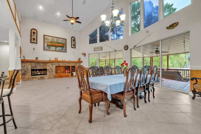 dining room with high vaulted ceiling, ceiling fan with notable chandelier, light tile patterned floors, and a fireplace