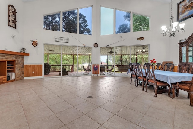 dining space with a towering ceiling, wood walls, and light tile patterned floors