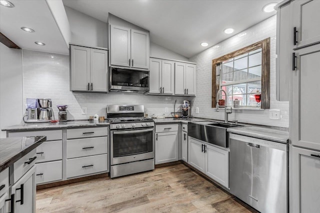 kitchen with tasteful backsplash, sink, stainless steel appliances, and light hardwood / wood-style floors