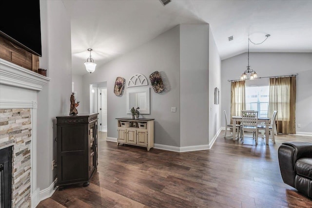 living room featuring lofted ceiling, a stone fireplace, and dark hardwood / wood-style floors