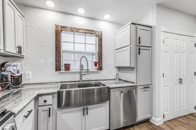 kitchen with tasteful backsplash, dishwasher, sink, dark hardwood / wood-style flooring, and light stone countertops