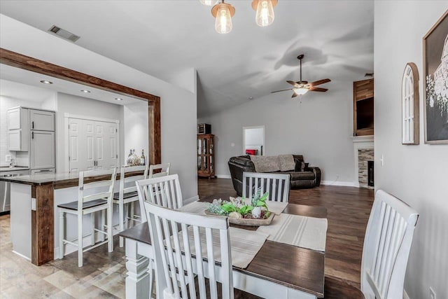 dining room featuring vaulted ceiling, ceiling fan with notable chandelier, and light hardwood / wood-style flooring