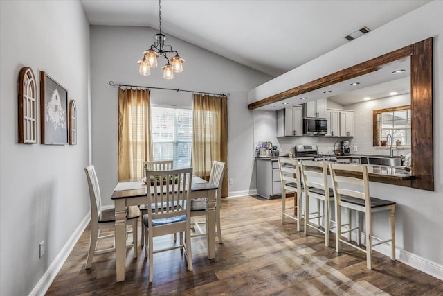 dining room with vaulted ceiling, a notable chandelier, sink, and hardwood / wood-style flooring