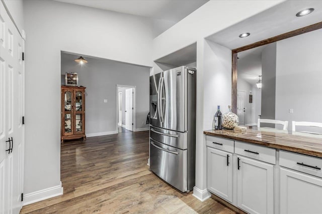 kitchen featuring hardwood / wood-style floors, white cabinets, and stainless steel fridge with ice dispenser