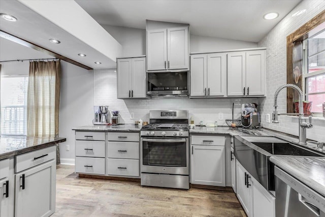 kitchen with stainless steel appliances, sink, backsplash, and light hardwood / wood-style floors