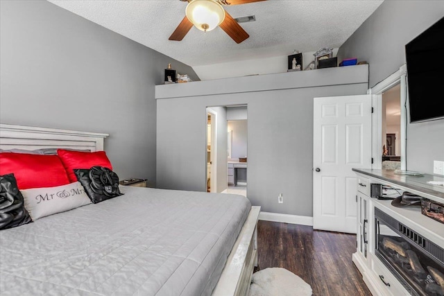 bedroom featuring dark wood-type flooring, ceiling fan, ensuite bathroom, a textured ceiling, and vaulted ceiling