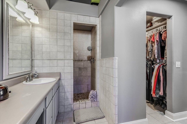 bathroom with tile patterned flooring, vanity, and a tile shower