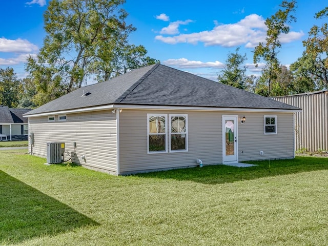 rear view of house featuring central AC unit and a lawn