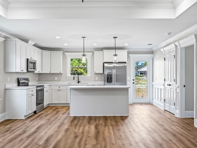 kitchen with white cabinetry, appliances with stainless steel finishes, decorative light fixtures, and a healthy amount of sunlight