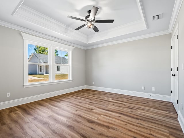 empty room featuring hardwood / wood-style floors, ceiling fan, crown molding, and a tray ceiling