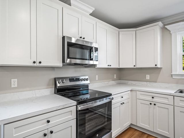 kitchen featuring light wood-type flooring, white cabinetry, light stone countertops, and stainless steel appliances