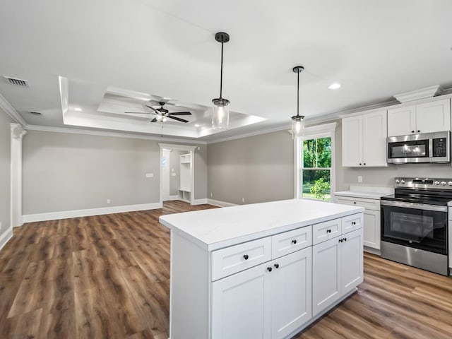 kitchen featuring white cabinetry, appliances with stainless steel finishes, crown molding, and a raised ceiling