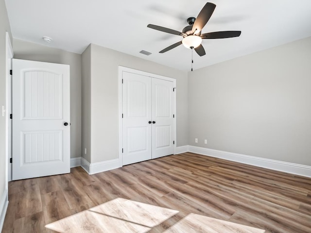 unfurnished bedroom featuring a closet, light hardwood / wood-style floors, and ceiling fan