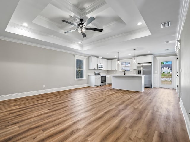 interior space featuring ornamental molding, light wood-type flooring, ceiling fan, and a raised ceiling