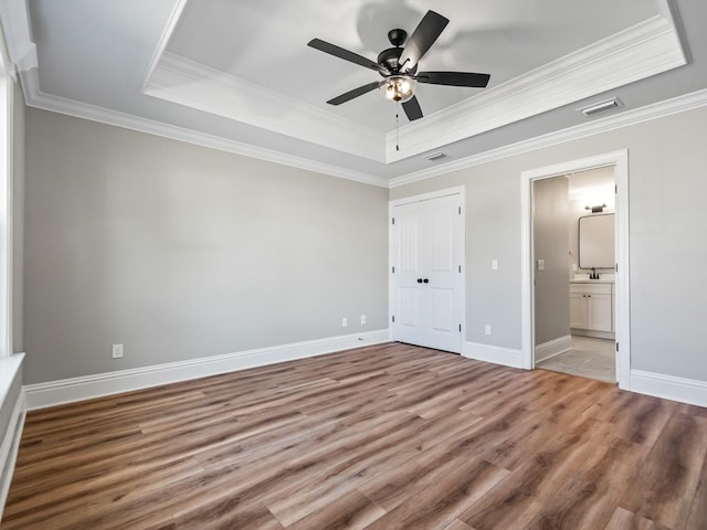 unfurnished bedroom featuring ceiling fan, a tray ceiling, and light hardwood / wood-style floors