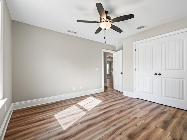 unfurnished bedroom featuring hardwood / wood-style floors, ceiling fan, and a closet