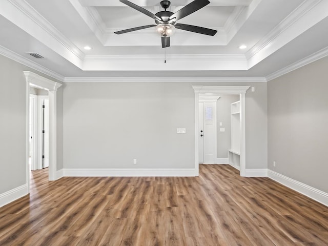 unfurnished room with hardwood / wood-style floors, decorative columns, ornamental molding, ceiling fan, and a raised ceiling