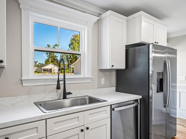 kitchen featuring white cabinets, appliances with stainless steel finishes, ornamental molding, and sink