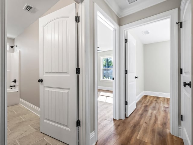 corridor featuring ornamental molding and light hardwood / wood-style floors