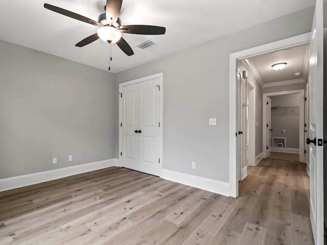 unfurnished bedroom with ceiling fan, light wood-type flooring, crown molding, and a closet